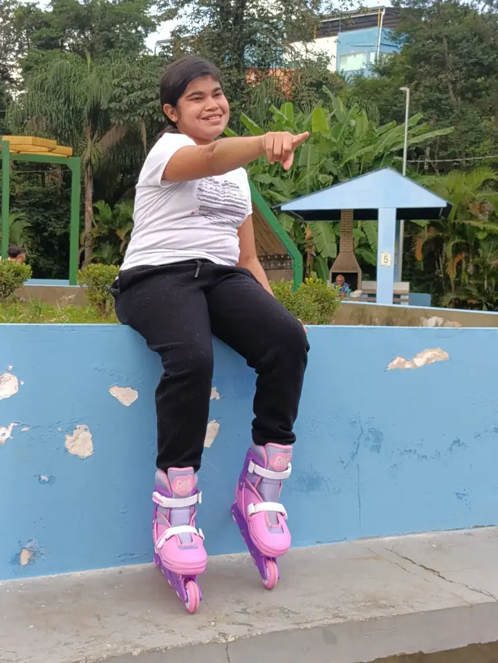 Clara de patins, sentada num muro azul